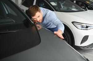 un' contento uomo sceglie un' nuovo elettrico auto a un' auto concessionaria. il concetto di acquisto un ecologico auto foto