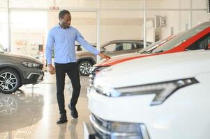 giovane afroamericano uomo è venuto per vedere automobili nel concessionaria o macchine showroom foto