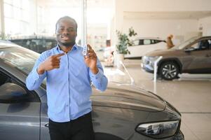 bello uomo è in piedi vicino il suo nuovo auto e sorridente foto