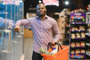 africano americano uomo shopping nel un' supermercato foto