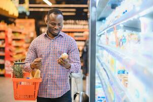 giovane africano uomo acquisto nel drogheria sezione a supermercato foto