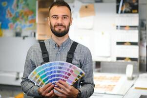 tipografo in piedi con colore campioni a il stampa produzione foto