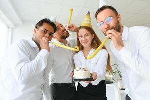 contento donna d'affari Tenere compleanno torta mentre fabbricazione sorpresa festa con sua colleghi nel il ufficio. foto
