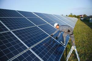 un indiano lavoratore nel uniforme e con utensili lavori su un' solare pannello azienda agricola foto