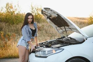 bellissimo sottile ragazza nel camicia e pantaloncini sembra nel Aperto auto cappuccio su un' strada foto