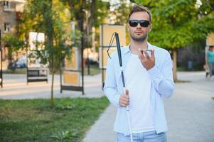 giovane bello accecato uomo a piedi con bastone nel cittadina foto