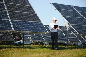 anziano maschio ingegnere ispeziona solare pannelli su azienda agricola. pulito energia. foto