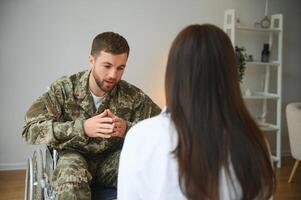 depresso tipo nel camuffare uniforme paralizzato soldato nel sedia a rotelle visitare femmina psicologo. foto