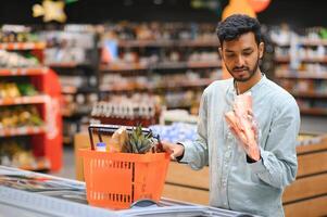 ritratto di contento bello giovane indiano a drogheria negozio o supermercato. foto