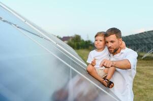 uomo mostrando poco bambino il solare pannelli durante soleggiato giorno. padre presentazione per il suo ragazzo moderno energia risorsa. poco passaggi per alternativa energia. foto