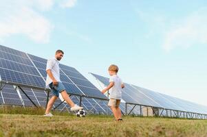 un' padre e il suo poco figlio giocare calcio vicino il solare pannelli. il concetto di rinnovabile energia. foto