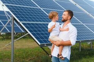 uomo mostrando poco bambino il solare pannelli durante soleggiato giorno. padre presentazione per il suo ragazzo moderno energia risorsa. poco passaggi per alternativa energia. foto