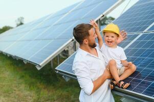 uomo mostrando poco bambino il solare pannelli durante soleggiato giorno. padre presentazione per il suo ragazzo moderno energia risorsa. poco passaggi per alternativa energia. foto