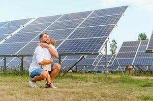 sorridente padre e il suo poco bambino su sfondo di solare pannelli. giovane padre godere la spesa tempo con il suo figlio. contento famiglia di Due su sfondo di solare pannelli. foto