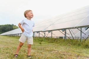 un' poco ragazzo è avendo divertimento vicino il solare pannelli. il concetto di solare energia. foto