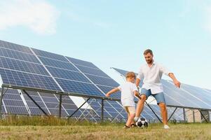 padre e figlio avere divertimento giocando calcio vicino il solare pannelli. il concetto di verde energia foto