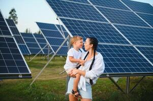 un' bambino e sua madre nel il fresco Aperto aria, accanto solare pannelli su un' soleggiato giorno a un' azienda agricola foto