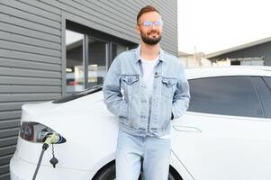 uomo ricarica elettrico auto di il Casa. foto