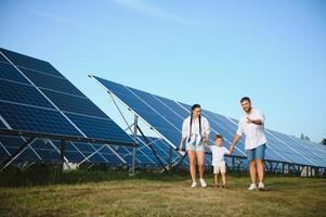 il concetto di verde energia. contento famiglia a piedi e avendo divertimento nel solare pannello campo. verde energia. foto