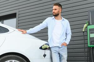 uomo in piedi di il suo elettrico auto foto