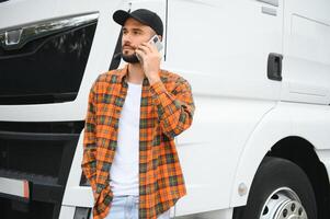 ritratto di giovane barbuto uomo in piedi di il suo camion. professionale camion autista in piedi di semi camion veicolo. foto