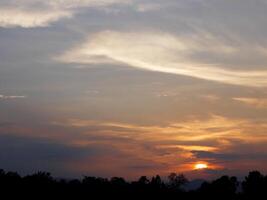 spettacolare tramonto Sopra, arancia sole crescente su al di sopra di il orizzonte foto