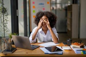 africano americano donna massaggio sua sopracciglia, fatica a partire dal opera, sensazione stressato su e vertiginoso a partire dal lavoro foto