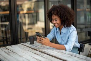 africano americano donna chiamata su il smartphone, sms su cellula Telefono, tipi testo Messaggio su cellula Telefono, gode in linea comunicazione, tipi risposta foto