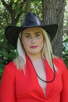 un' bellissimo cowgirl nel un' nero cappello e un' rosso vestire. foto