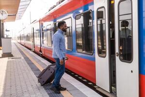 contento uomo con valigia entrata in il treno su stazione. foto