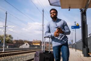 arrabbiato uomo con un' valigia e mobile Telefono in piedi su un' ferrovia stazione. foto