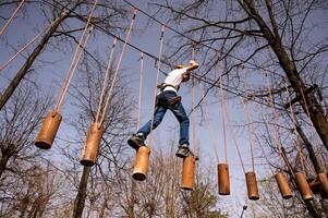 un' ragazzo nel un' casco si arrampica un' corda parco nel il primavera foto