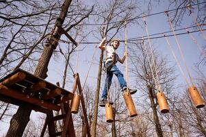 un' ragazzo nel un' casco si arrampica un' corda parco nel il primavera foto