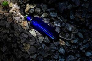 profumo buio blu trasparente bottiglia nel ghiaia o corallo sfondo foto