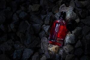 profumo rosso trasparente bottiglia nel ghiaia o corallo sfondo foto