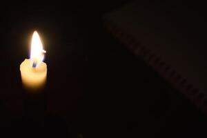 singolo candela con fiamma nel il buio posto, isolato nero sfondo foto