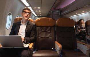 uomo d'affari Lavorando con il computer portatile mentre seduta nel aereo posto a sedere. attività commerciale opera e viaggio concetto foto