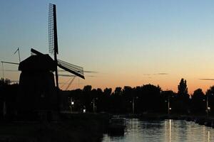 tramonto nel un' olandese paesaggio, mulino a vento e canale foto