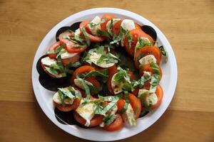 italiano cibo come un' antipasto insalata caprese, pomodori, Mozzarella formaggio e basilico con aceto e oliva olio foto