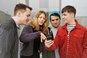 gruppo di adolescenziale amici avendo un' discussione al di sopra di alcuni mobile Telefono soddisfare foto