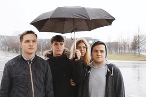 gruppo di giovane urbano adolescenziale amici sotto uno ombrello foto