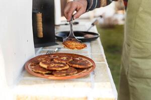 un' uomo cuochi Pancakes nel un' frittura padella. posti fritte Pancakes su un' piatto foto