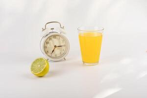 allarme orologio, lime e arancia succo su un' leggero sfondo. è tempo per mattina prima colazione. salutare stile di vita. posto per testo foto