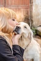 donna bionda che bacia il suo cane da riporto foto