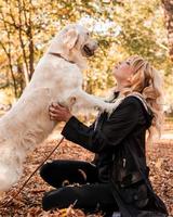 una bella donna con il suo cane labrador retriever sdraiato nel parco