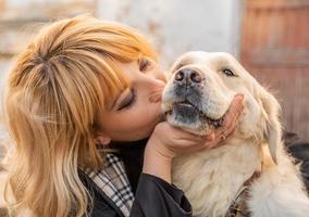 donna bionda che bacia il suo cane da riporto foto