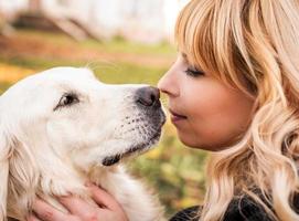 una donna bionda che si diverte con il suo cane da riporto nel parco foto