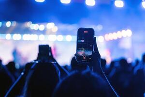 persone Tenere inteligente Telefono e registrazione e Fotografare nel musica Festival concerto foto