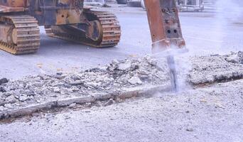 scavatrice idraulico schiacciante martello è rottura asfalto strada per preparazione per installare acqua tubatura sistema progetto foto