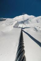 acciaio cavo di un' cavo auto avvicinamento. corda struttura. il sentiero di il cavo cabina contro il fondale di snow-capped montagne foto